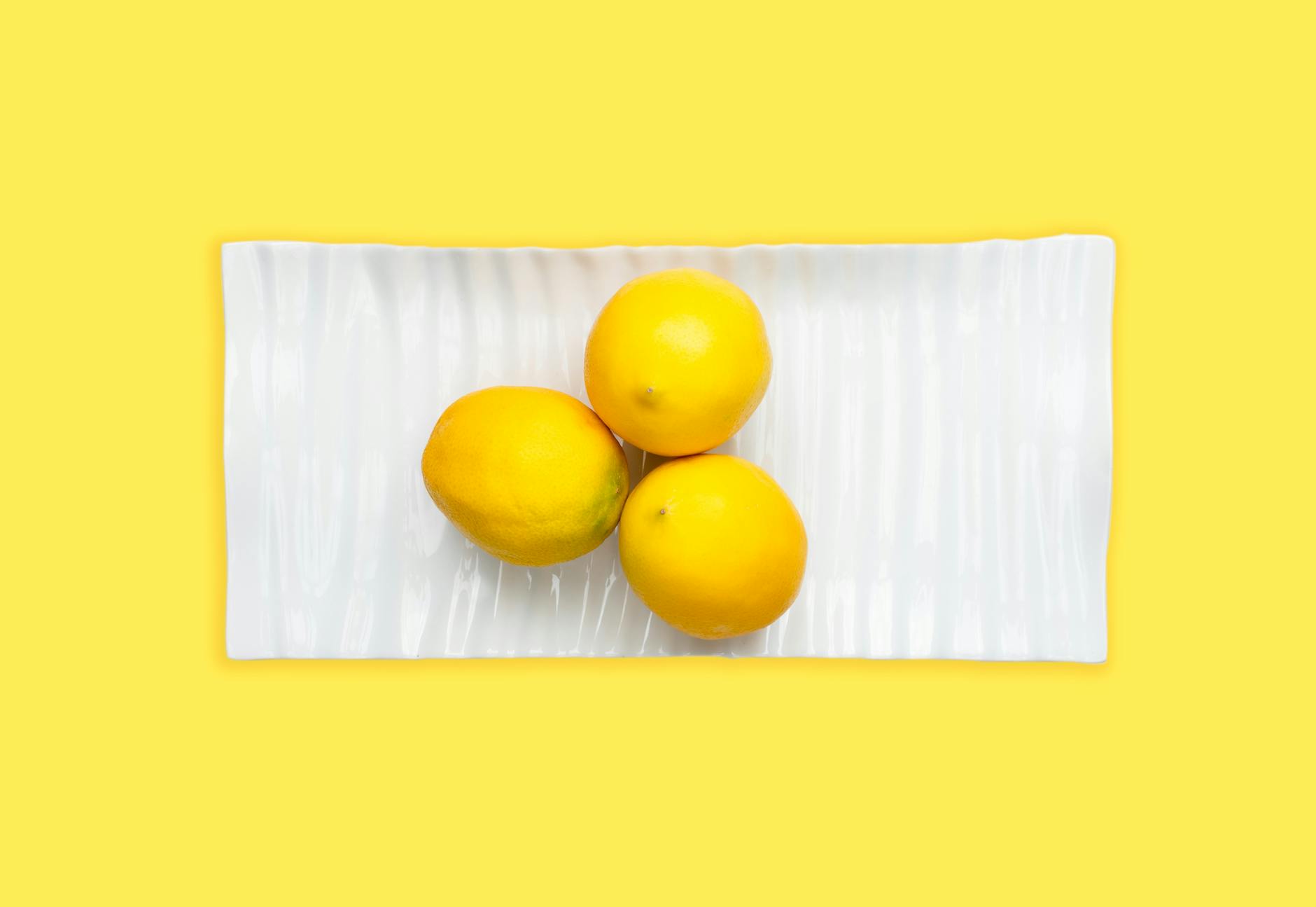 Fresh lemons on a white plate with vibrant background