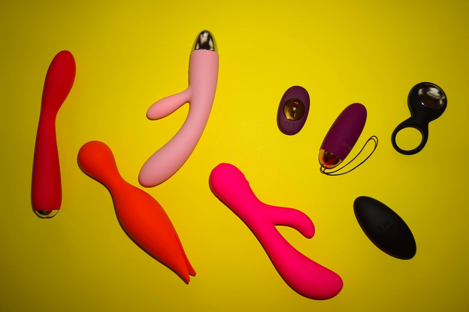 Vibrant collection of various clitoral vibrators on yellow surface showing design diversity