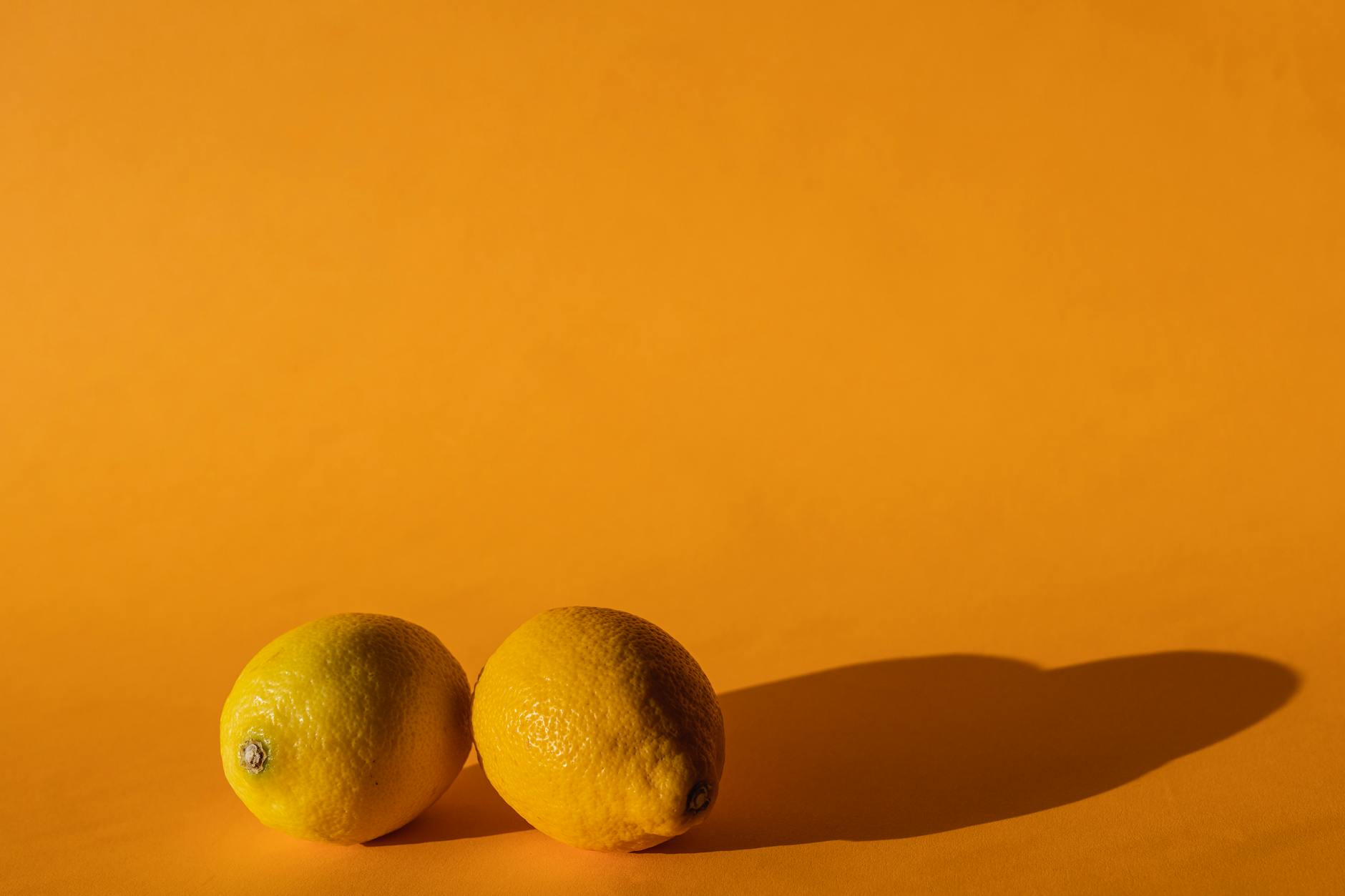 Ripe vivid lemons composed on bright yellow background in modern studio daylight